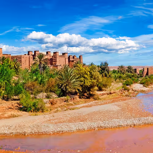Panoramic view of Aït Benhaddou kasbah and palm-lined Ounila River valley near Ouarzazate in Morocco’s Drâa-Tafilalet region, a top UNESCO day trip and desert gateway experience.