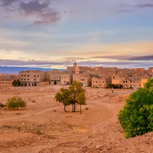 Panoramic view of Zagora town in the Drâa-Tafilalet region, Morocco, with desert landscape and traditional kasbah-style buildings at sunset, a gateway to Sahara excursions and the Draa Valley.