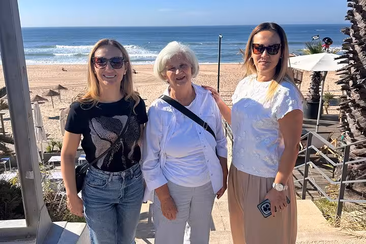 Three women enjoy a sunny day at a Lisbon beach, a perfect stop on the 007 Sintra and Atlantic Coast private tour.