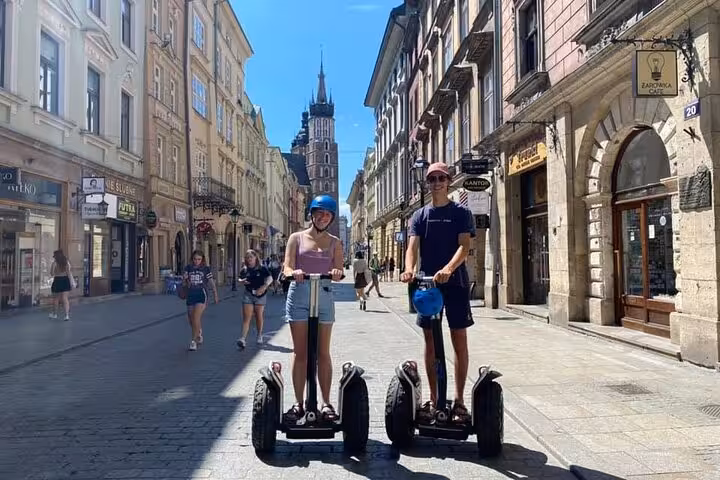 Two tourists on Segways enjoy the 120 min Old Town Segway Tour in Krakow, with St. Mary's Basilica in the background.