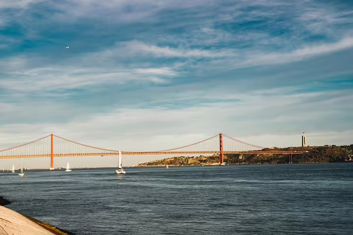 Scenic view of the 25 de Abril Bridge over the Tagus River on a sunny day in Lisbon's Belém District.