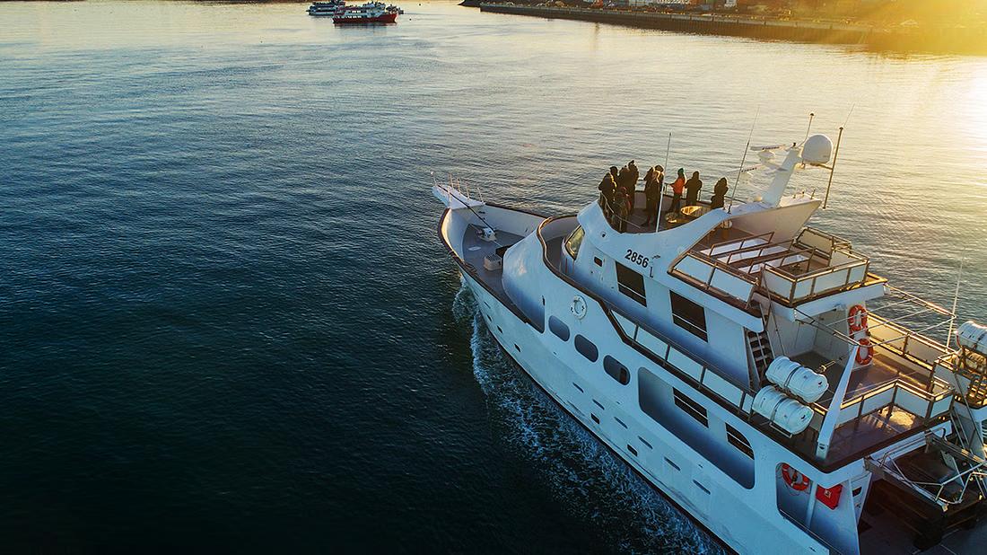 An aerial shot of a yacht with people onboard the deck