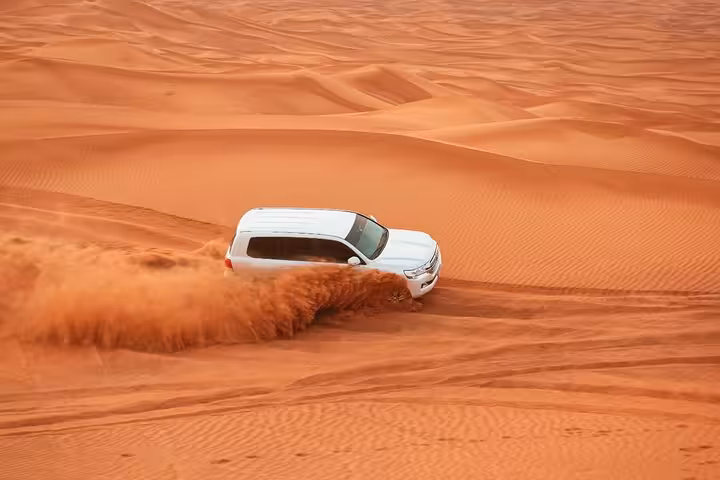 4x4 dune bashing in Ras Al Khaimah desert safari tour, SUV carving through red sand dunes