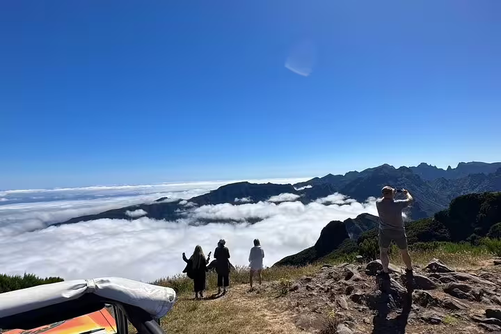 Tourists enjoy breathtaking views above the clouds on a 4x4 Jeep tour to Porto Moniz and Fanal, Madeira's stunning landscapes.