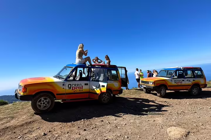 Adventure seekers enjoy panoramic views from colorful 4x4 vehicles on the Northwest Madeira off-road exploration tour.