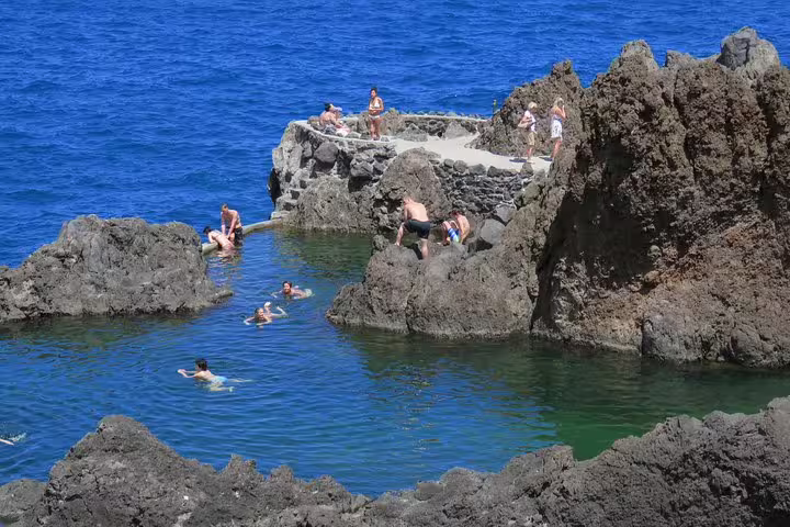 Tourists enjoying a 4x4 adventure at Northwest Terraces' volcanic pools, swimming amidst stunning natural rock formations.