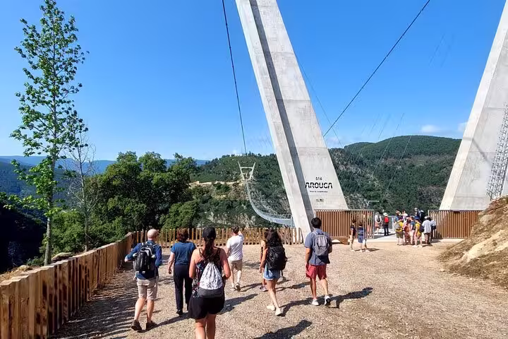 Tourists walking towards the towering entrance of the 516 Arouca Suspension Bridge in Portugal.
