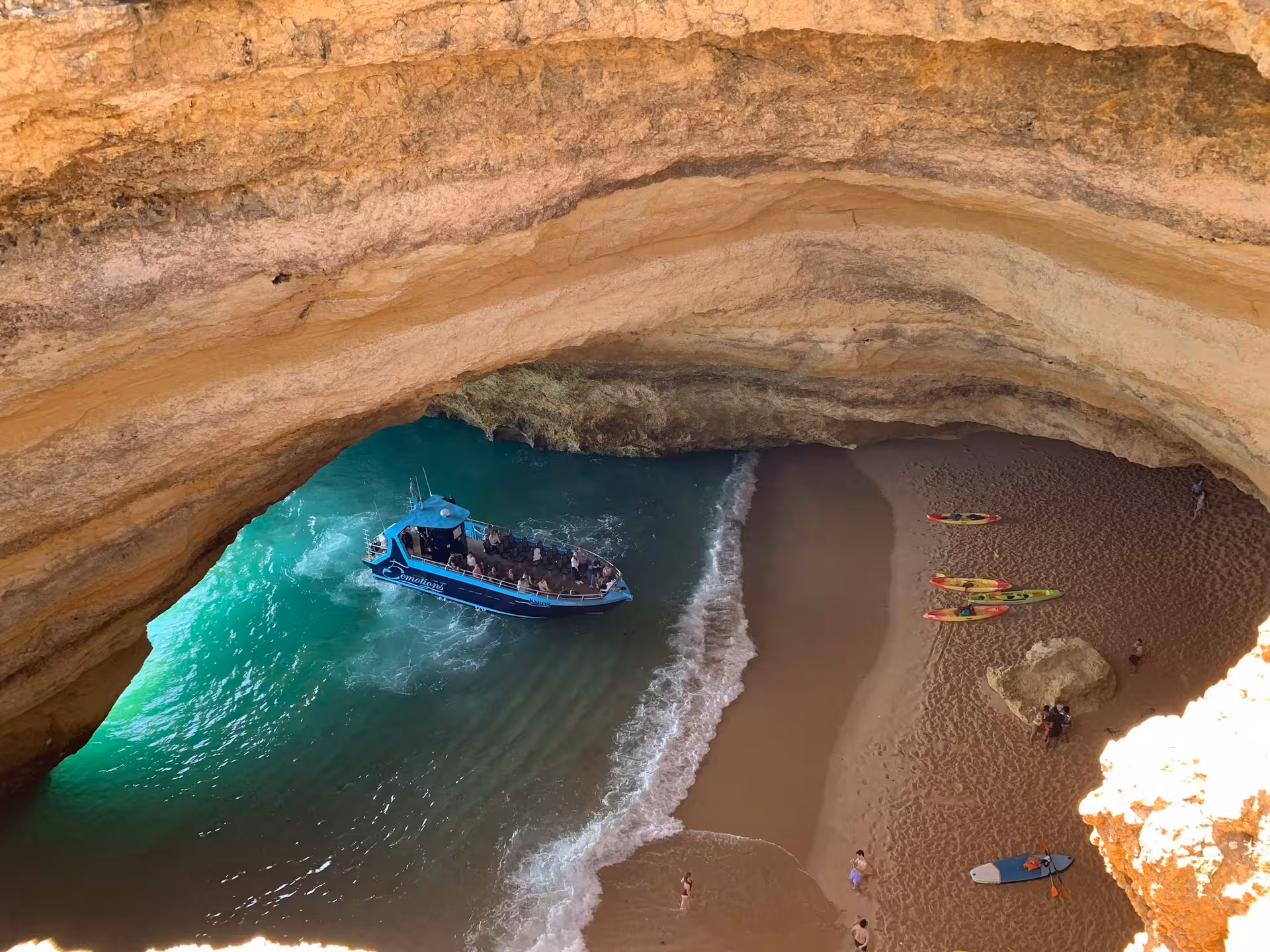 Aerial view of a boat and kayaks inside Benagil Cave, highlighting adventure tours along the Algarve Coast's natural wonders.