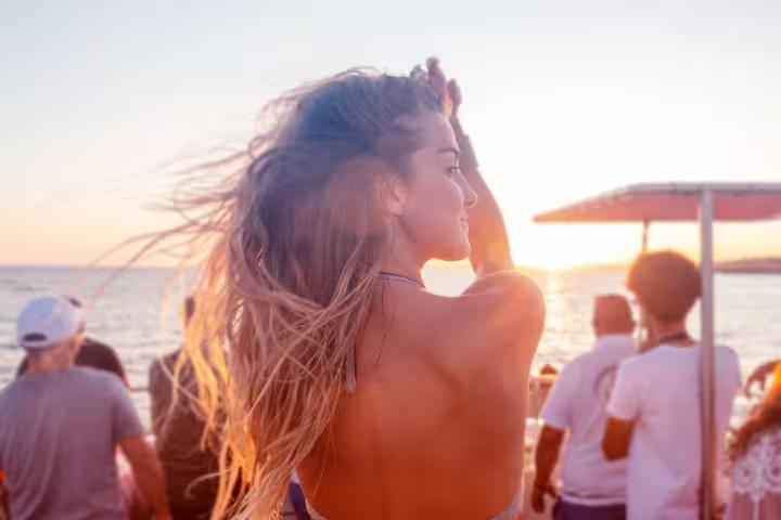 Woman enjoying a stunning sunset on the Portimao boat party with friends dancing on deck.