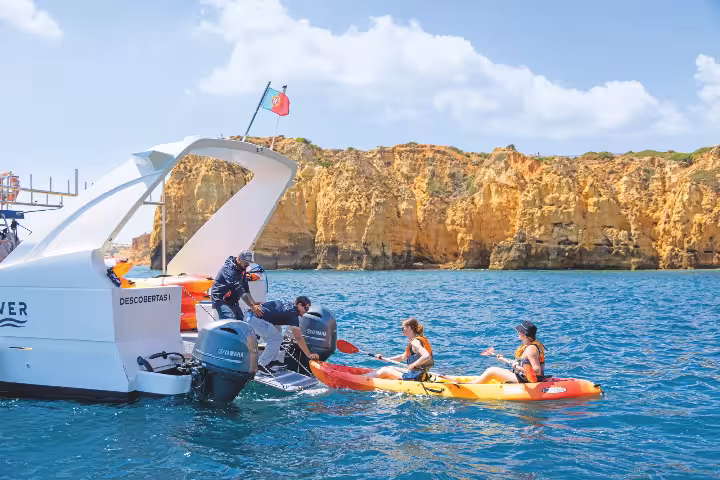 Kayakers launching from a boat near golden cliffs in Lagos Algarve Portugal on a sunny kayak tour adventure