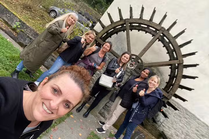 Happy group posing at Aarau’s old waterwheel, enjoying a self-guided scavenger hunt and city sights walking tour