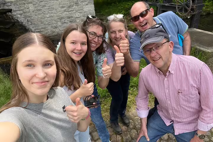 Happy group giving thumbs up near Aarau waterwheel on a self-guided scavenger hunt and sights tour