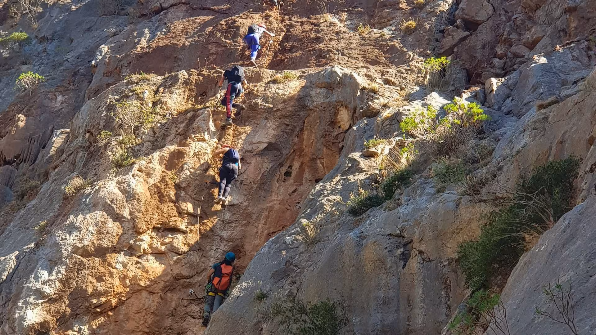 Participants scaling a vertical rock face in Gutturu Xeu canyon, Iglesias, highlighting the ultimate abseiling adventure.