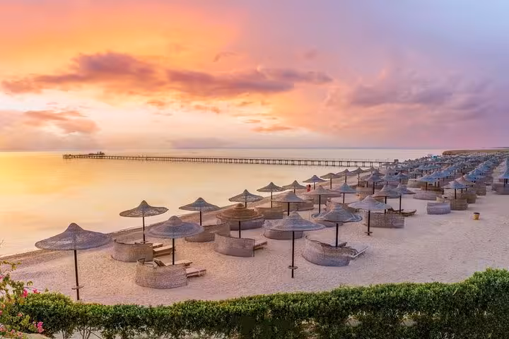 Abu Dabab beach at sunset with sun umbrellas and calm Red Sea views on a semi-private day trip from Hurghada