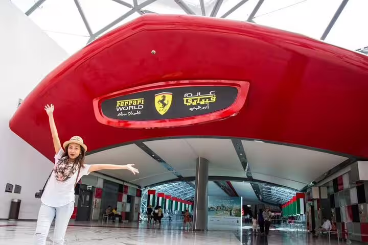 Visitor excitedly poses at the entrance of Ferrari World Abu Dhabi, highlighting the thrilling adventure of the 4x4 tour.