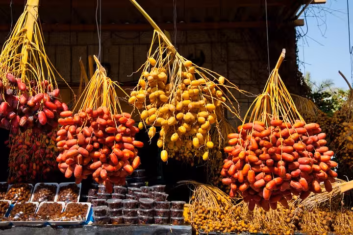 Vibrant bunches of dates hanging in a market stall, showcasing local produce on the Abu Dhabi city tour by bus.