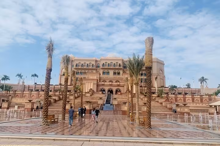 Private Abu Dhabi city tour visit to Emirates Palace exterior with palm-lined plaza and fountains