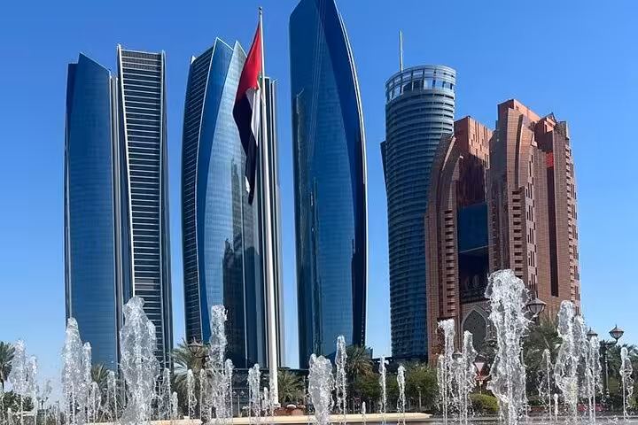 Abu Dhabi city tour stop at Etihad Towers skyline with UAE flag and fountains on Corniche