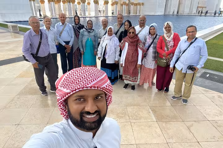 Abu Dhabi city tour group photo at Sheikh Zayed Grand Mosque courtyard with local guide