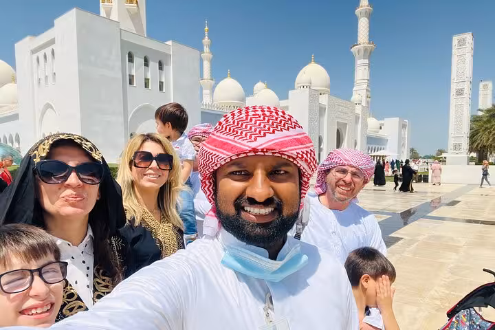 Private Abu Dhabi city tour guests selfie at Sheikh Zayed Grand Mosque entrance with minarets