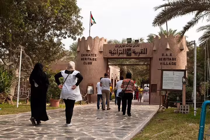 Visitors explore the entrance of the UAE Heritage Village in Abu Dhabi during a 4x4 city tour from Dubai.