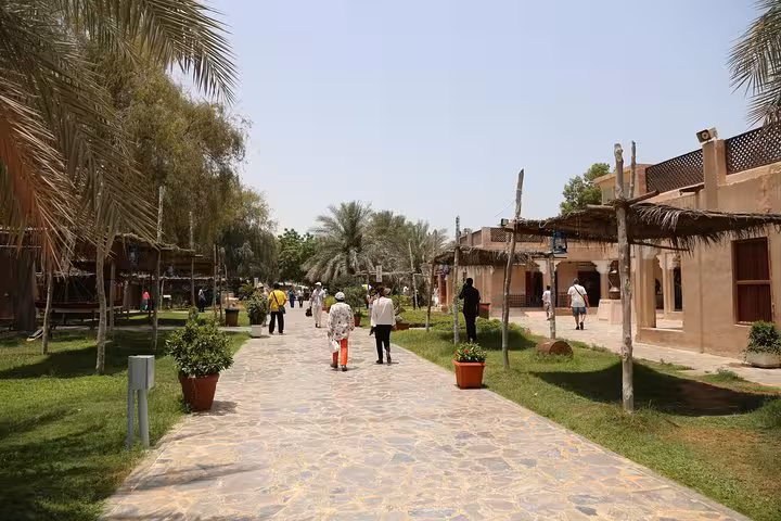 Visitors exploring the lush greenery and traditional architecture of Abu Dhabi's Heritage Village on a half-day city tour.