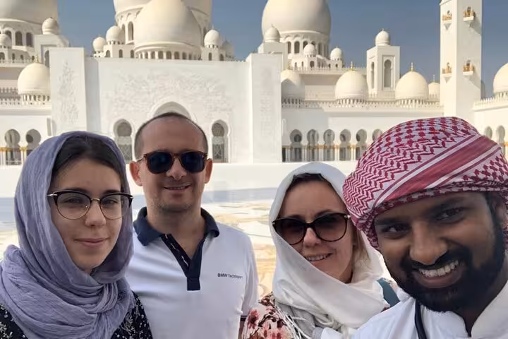 Private Abu Dhabi tour guests with local guide at Sheikh Zayed Grand Mosque, multilingual city sightseeing