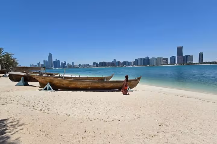Wooden dhow on Abu Dhabi beach with skyline view, city tour from Ras Al Khaimah and Corniche stop