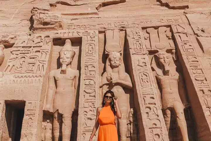 Traveler by carved statues and hieroglyphs at Abu Simbel, private tour from Aswan with guide and transfers