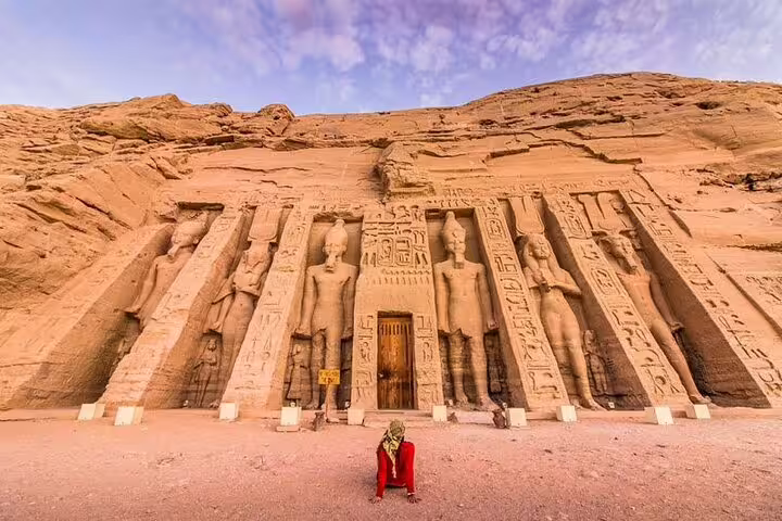 Traveler at Abu Simbel Temple facade carved into sandstone cliffs, iconic Abu Simbel day tour from Aswan Egypt