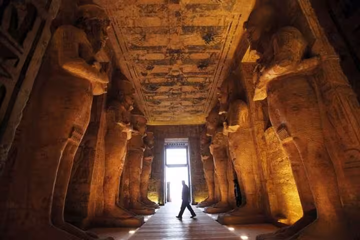 Traveler walking through Abu Simbel Temple interior lit corridor on a private full-day Abu Simbel tour from Aswan