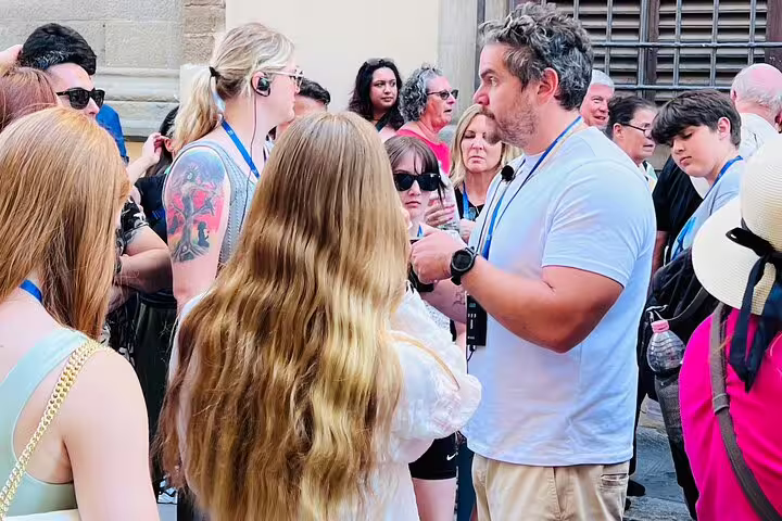Expert guide leading a small group on an Academia Gallery skip-the-line tour in Florence with headsets for live commentary