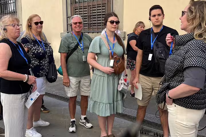 Visitors wearing audio headsets listen to a guide before entering Florence’s Academia Gallery on a skip-the-line tour