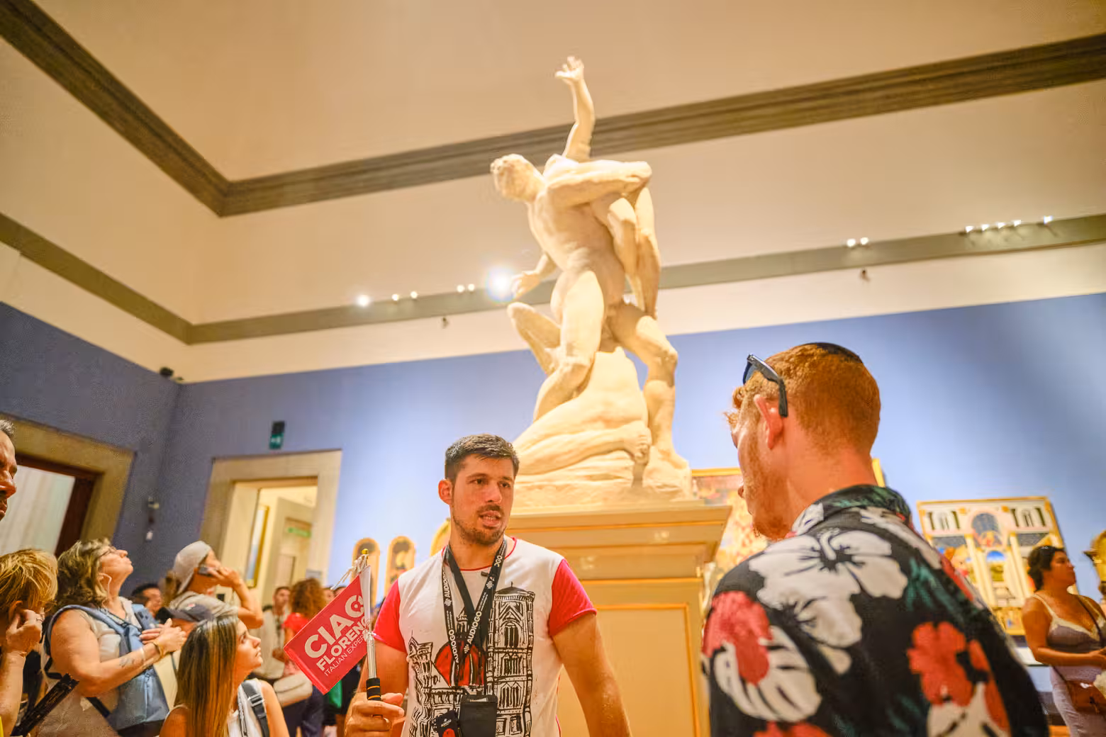 Visitors explore an impressive sculpture with a guide at Accademia Gallery in Florence on a skip-the-line tour.