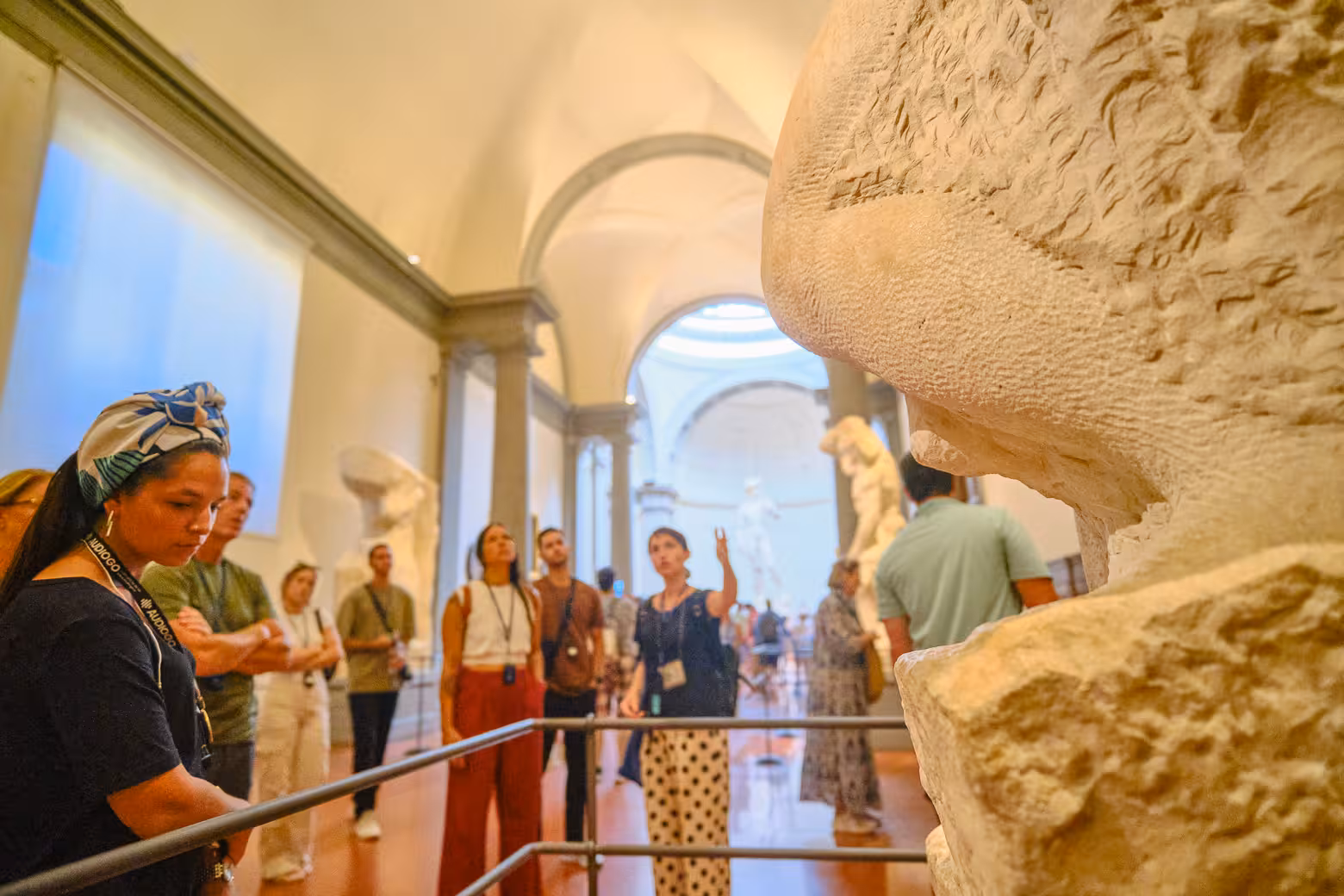 Visitors admire sculptures in Accademia Gallery Florence on a guided skip-the-line tour, led by an expert guide.