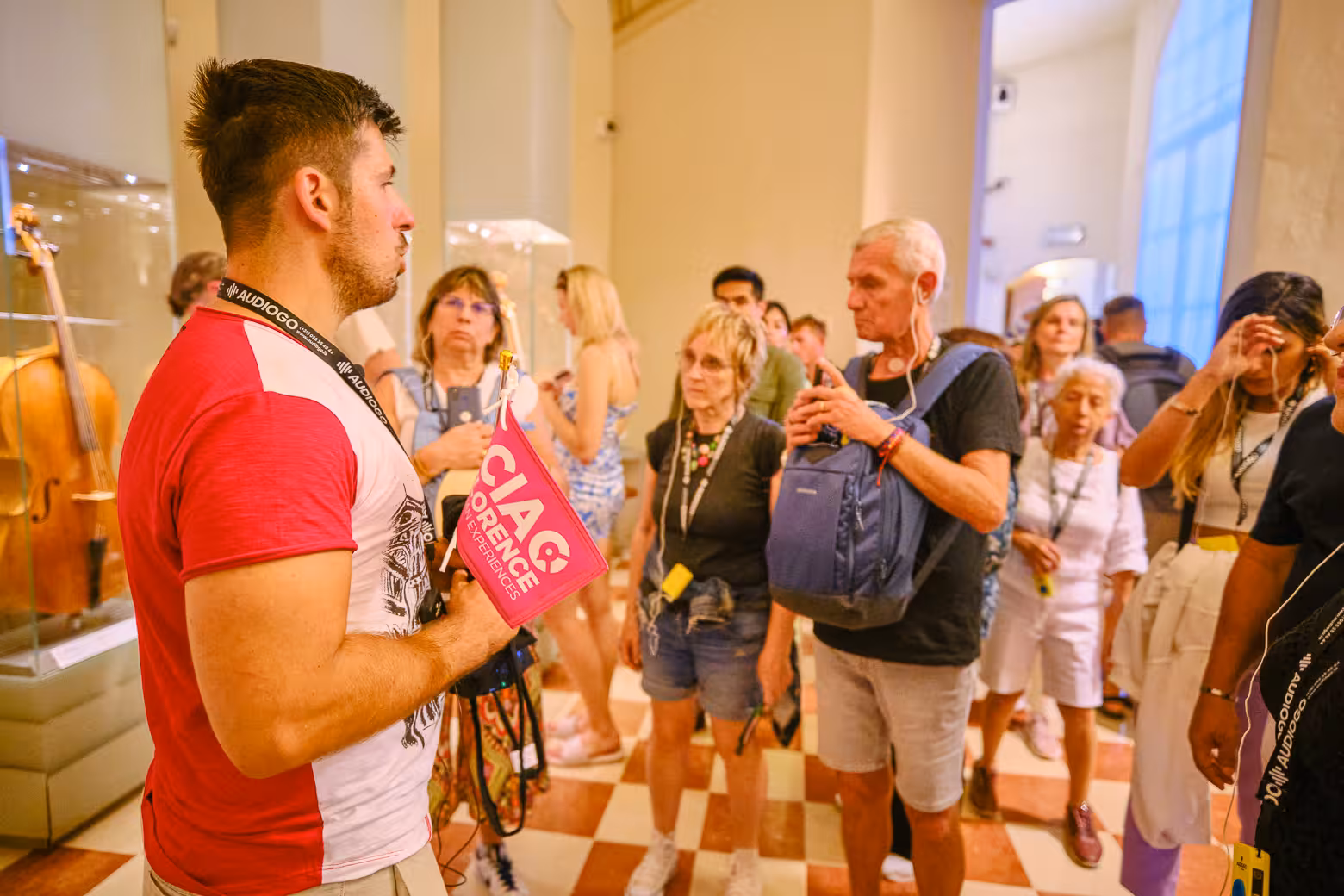 Visitors engage with a guide holding a flag during a private Accademia Gallery tour in Florence, showcasing fine art.