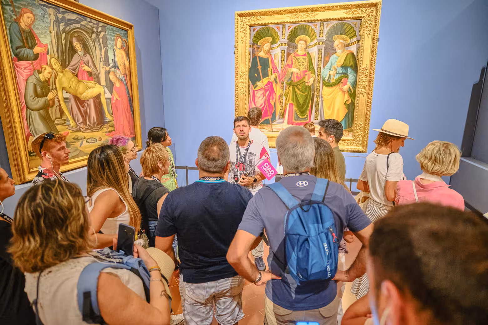 Group gathered around guide in Accademia Gallery, Florence, observing Renaissance paintings on private skip-the-line tour.