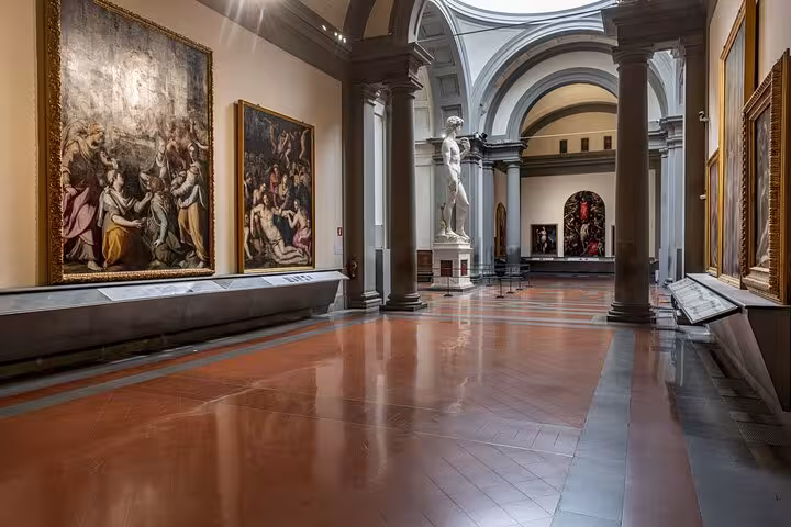 Spacious hall of Accademia Gallery featuring renowned sculptures and paintings in Florence, Italy.