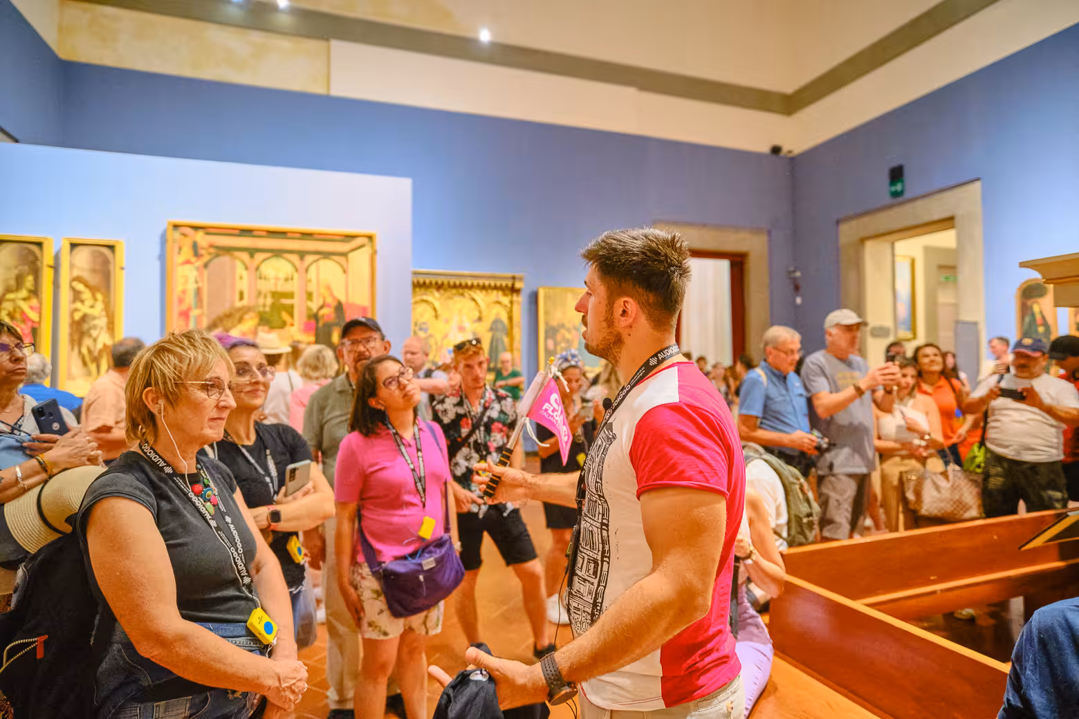 Tour group listens to guide in Accademia Gallery, Florence, surrounded by Renaissance art on a skip-the-line tour.
