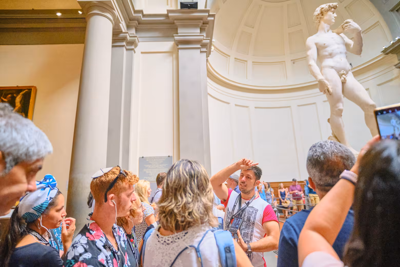Tourists engage with a guide near Michelangelo's David on a skip-the-line tour at Accademia Gallery, Florence.