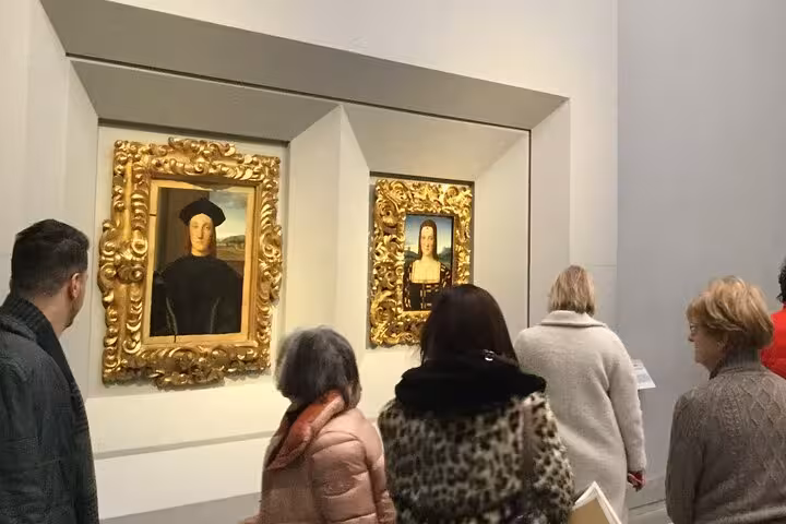 Visitors admire Renaissance paintings in ornate frames during the Accademia & Uffizi Galleries private guided tour.
