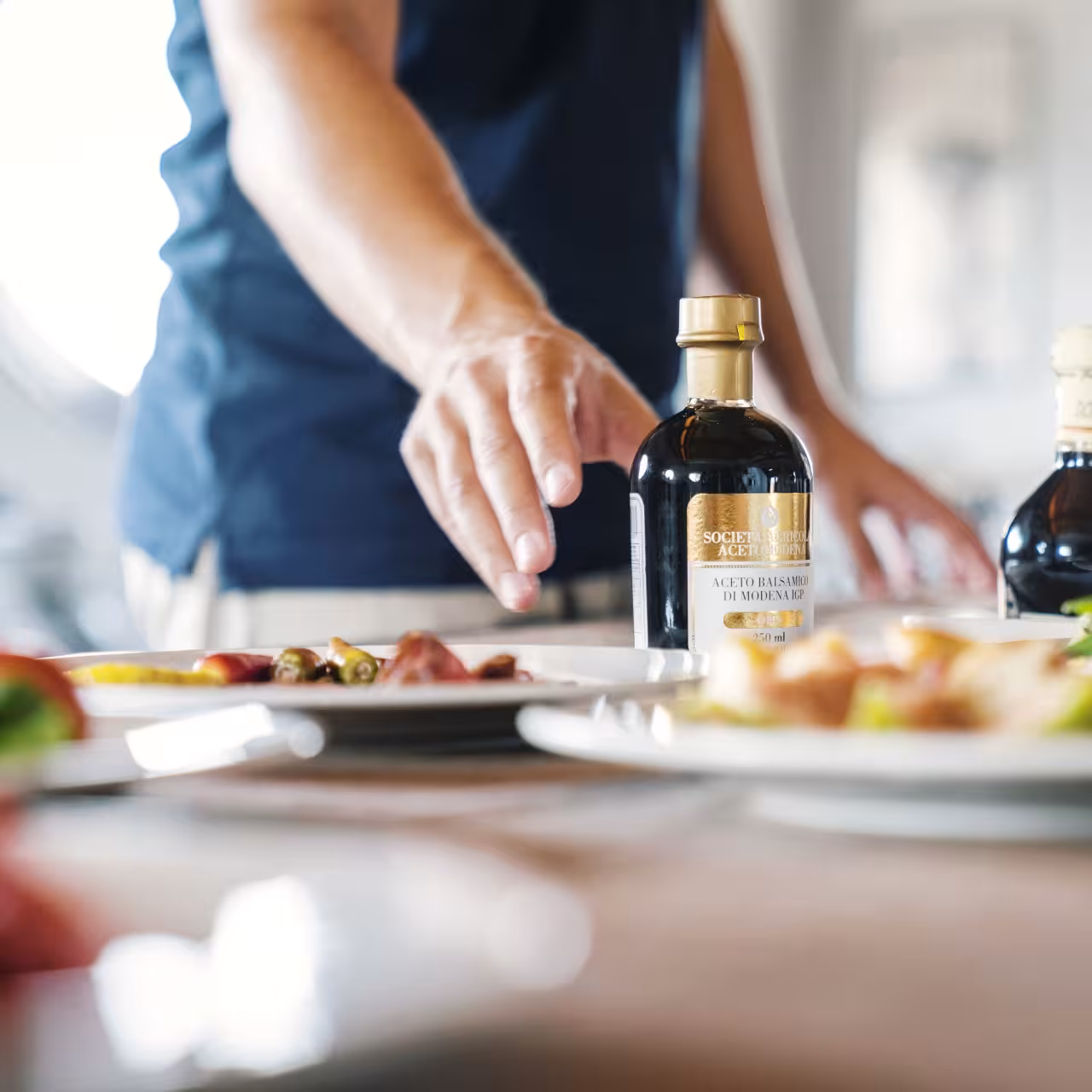 Close-up of Aceto Balsamico di Modena bottle beside tasting plates on a Modena food tour with gelato