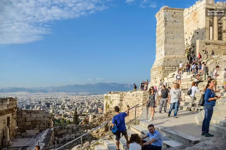 Visitors on Acropolis steps with panoramic Athens view during a guided walking tour led by a French guide