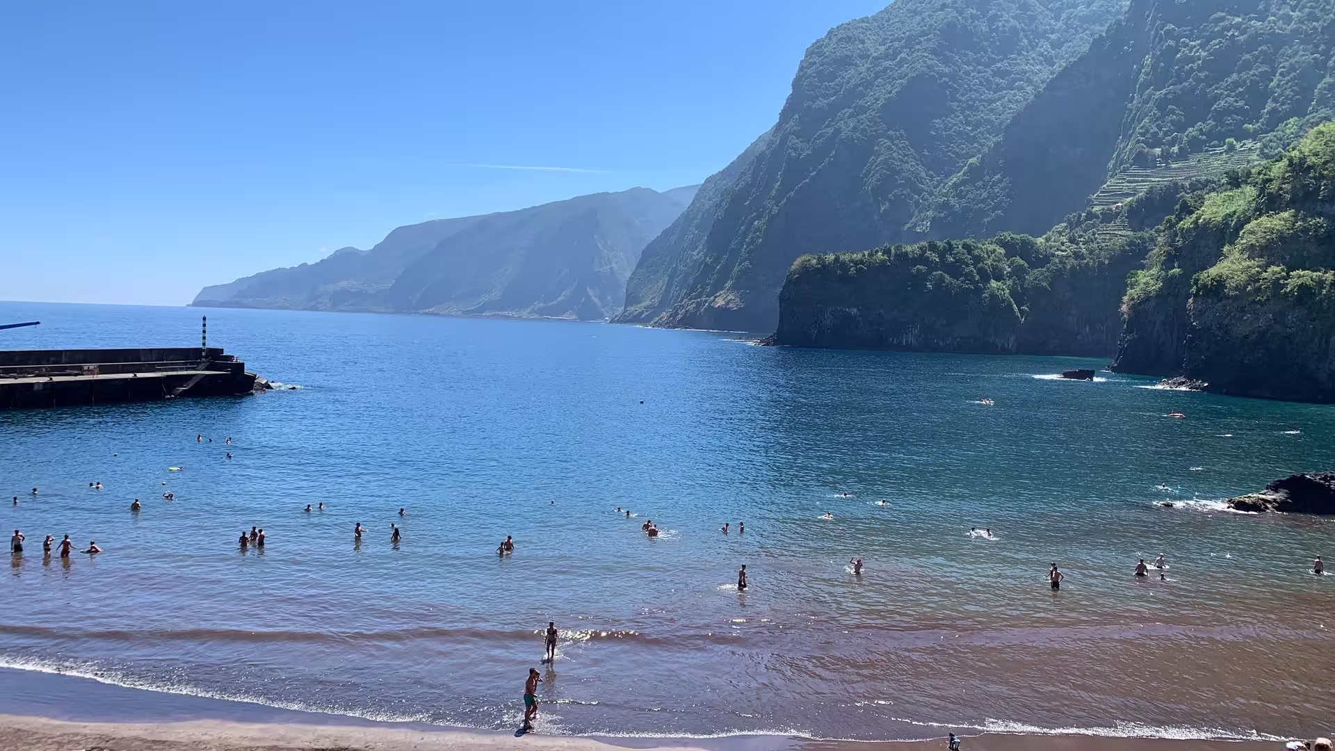 People enjoying a sunny day on the beach with scenic coastal cliffs in the background, perfect for an active north adventure.