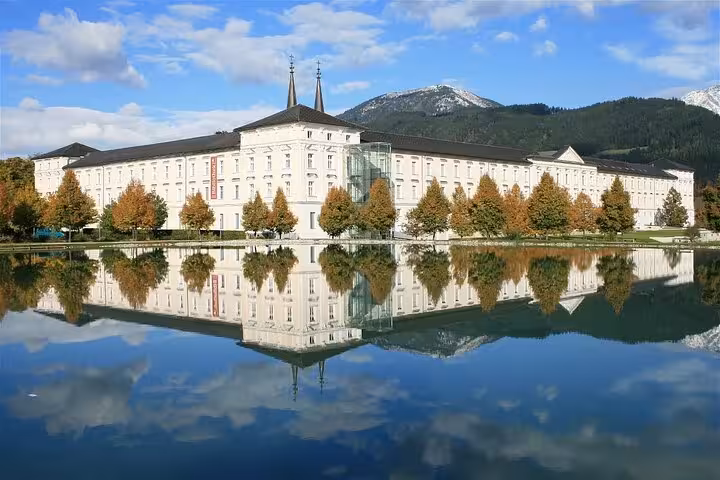 Admont Abbey exterior reflected in calm lake, highlight of private day tour from Salzburg to Hallstatt