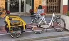 Adult city bike rental with child trailer parked on a sidewalk, ideal for family urban cycling tours