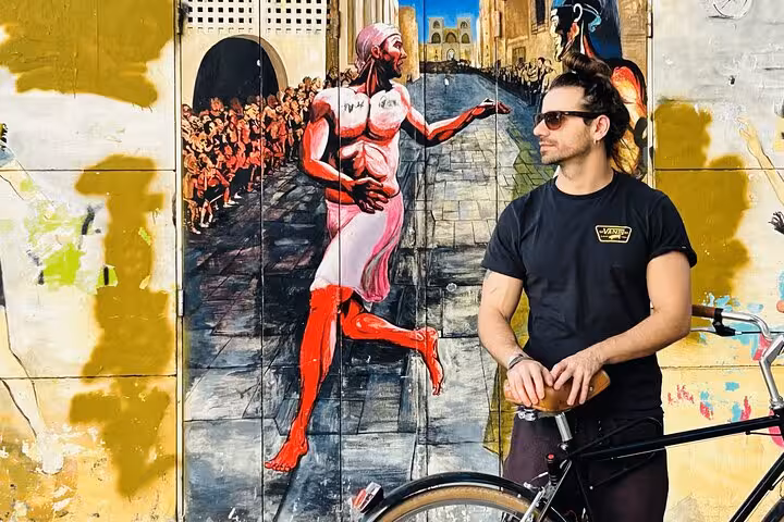 Adult city bike rental rider posing by colorful street art mural, perfect for urban sightseeing and photo stops