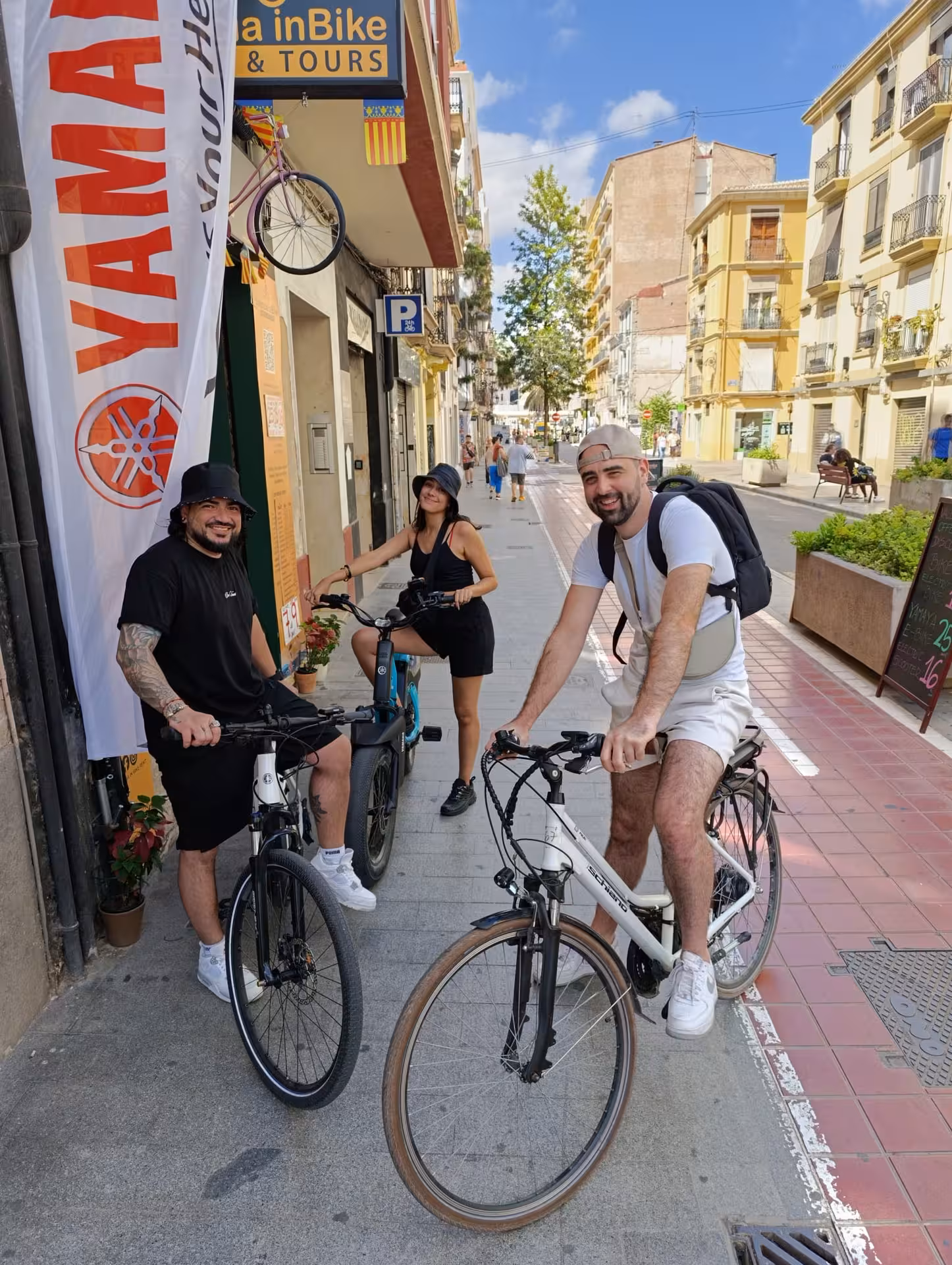 Happy travelers with adult city bike rentals outside Valencia bike shop, ready for a self-guided ride