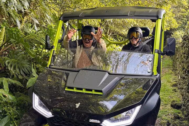 Excited passengers in a buggy drive through dense greenery during an adventure tour in Mount Pico.