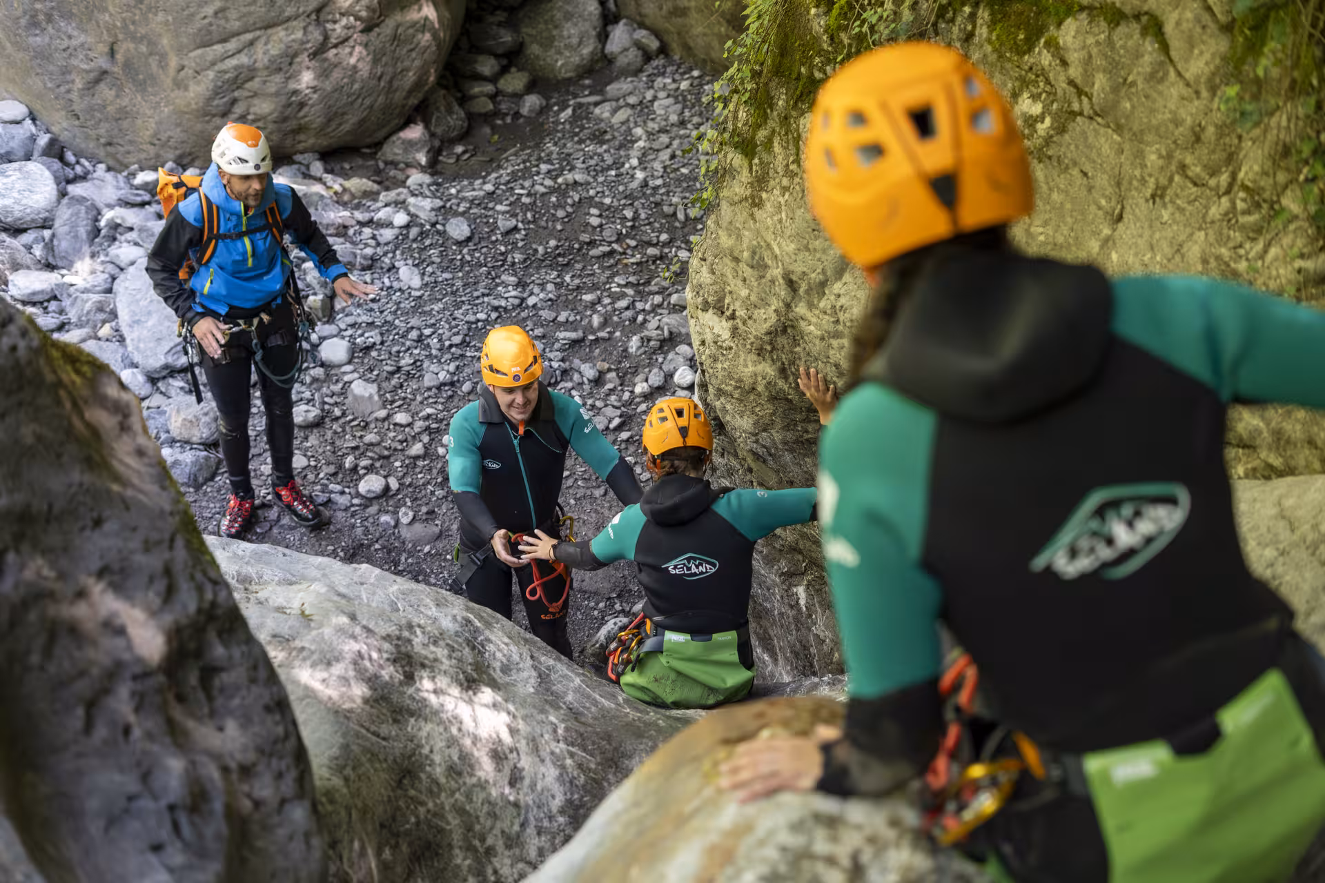 Adventure seekers canyoning in Interlaken, navigating rocky terrain with safety gear and teamwork.